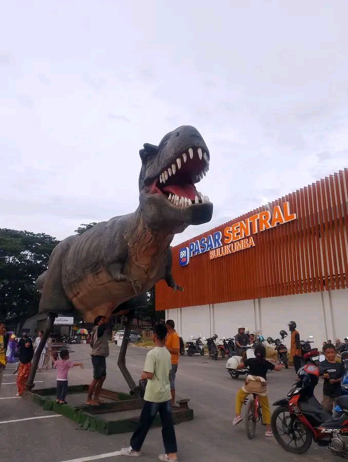 Warga berfoto dengan latar replika Dinosaurus di Pasar Sentral Bulukumba. Foto Maya M Tawil/FB